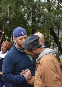 Church Planter Josh Holland prays with a man on the streets of New Orleans as Level Ground Community Church, 2 years old participates in a gift distribution.